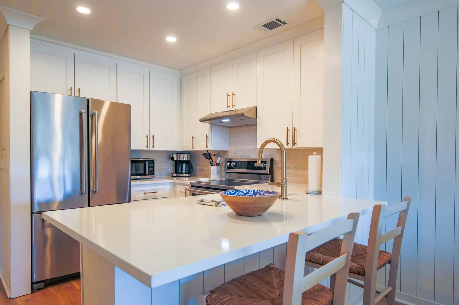 The kitchen features stainless steel appliances, white cabinetry and a tiled backsplash.