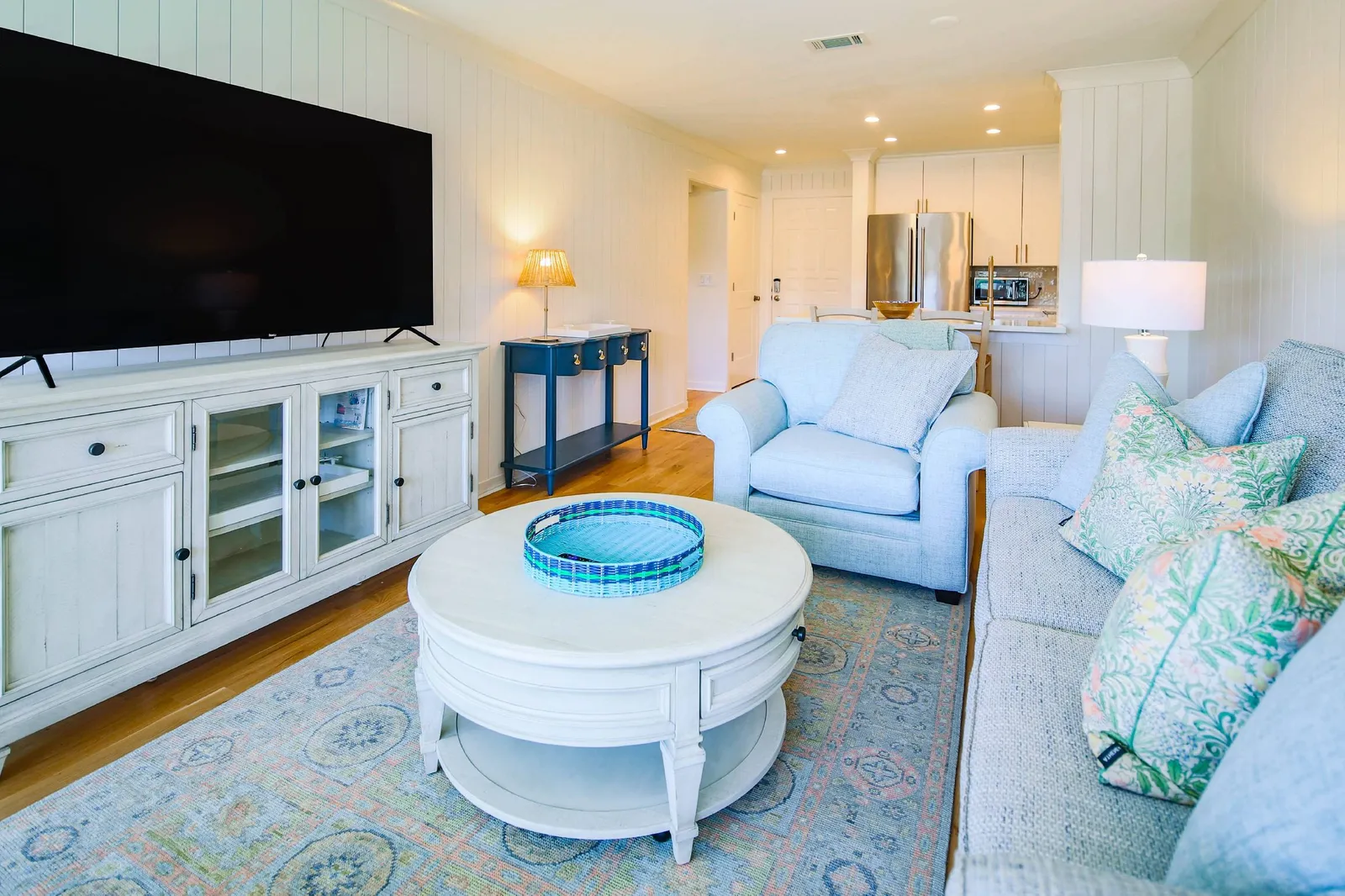 The living room features a sofa, arm chair and large screen smart TV.