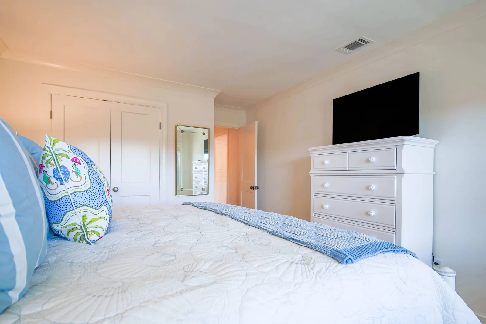 The bedroom also features a dresser and a smart TV.