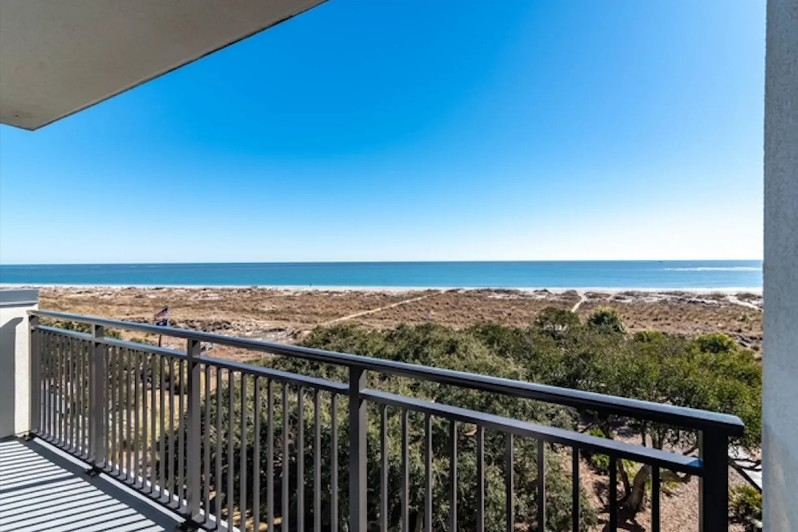 The partially covered balcony overlooks the sand dunes, beach access points and ocean.