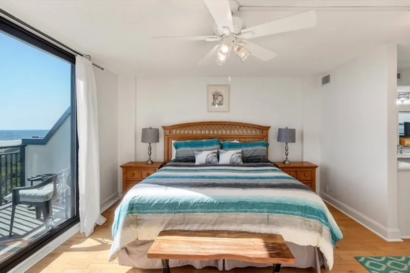 The primary suite features a king bed, night stands with reading lamps and a ceiling fan.