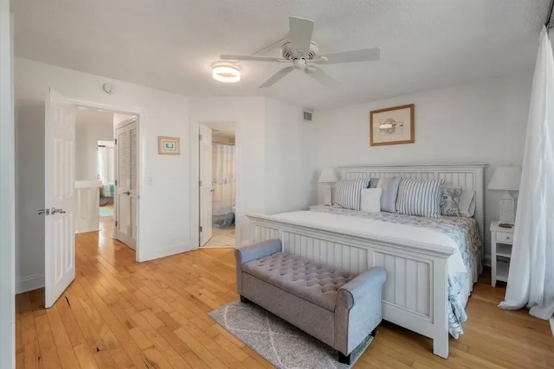 The guest suite features a king bed, nightstands with reading lamps, bench and ceiling fan.