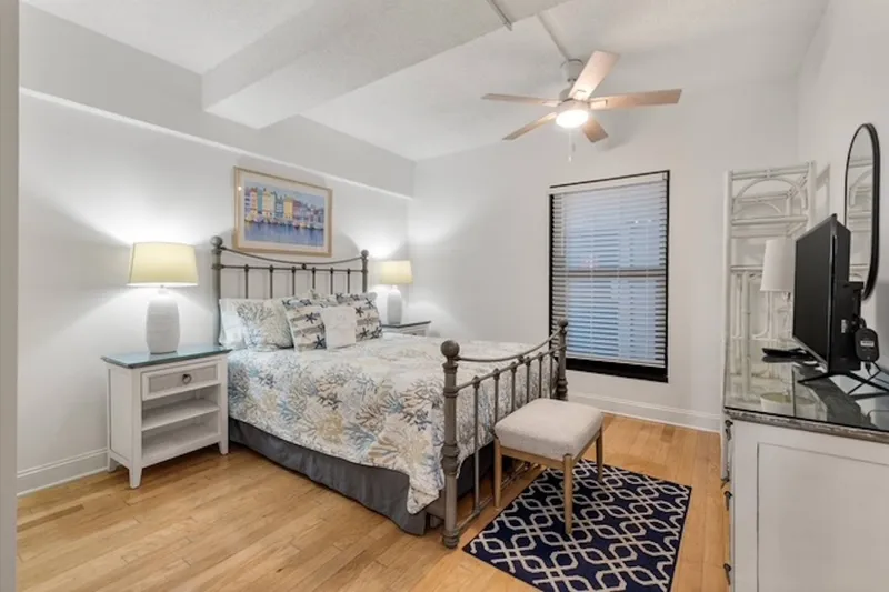 The guest bedroom features a queen bed, night stands with reading lamps, a dresser and smart TV.