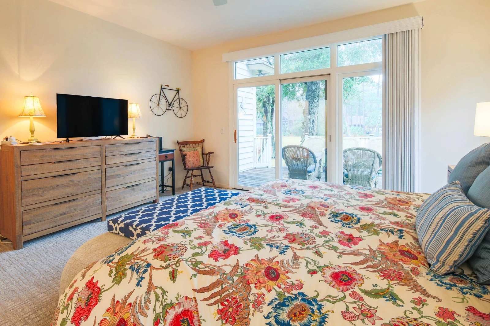 The primary suite features a king bed, access to the back deck, a dresser and smart TV.