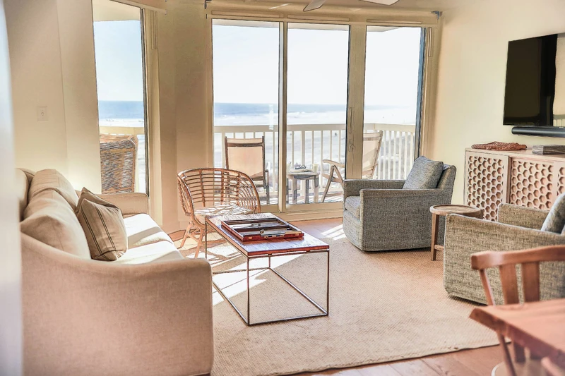 The living room features a spacious seating area, large screen TV, ocean views and access to the balcony.