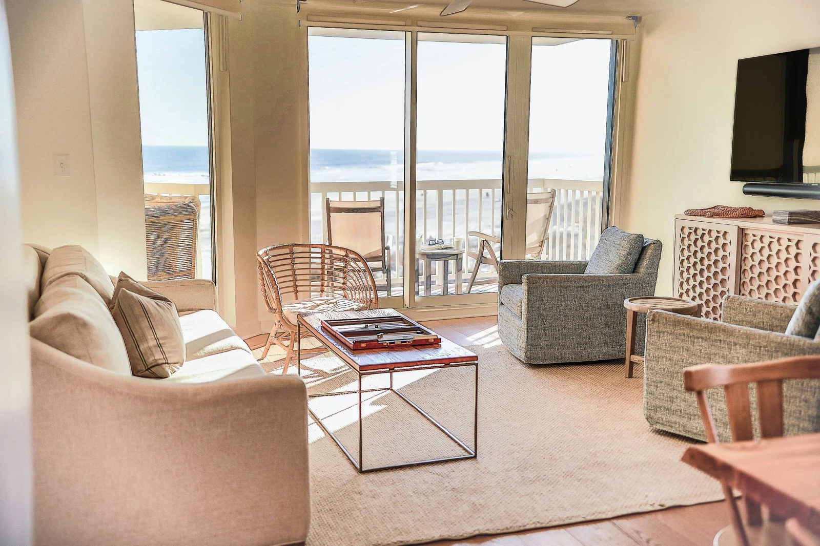 The living room features a spacious seating area, large screen TV, ocean views and access to the balcony.