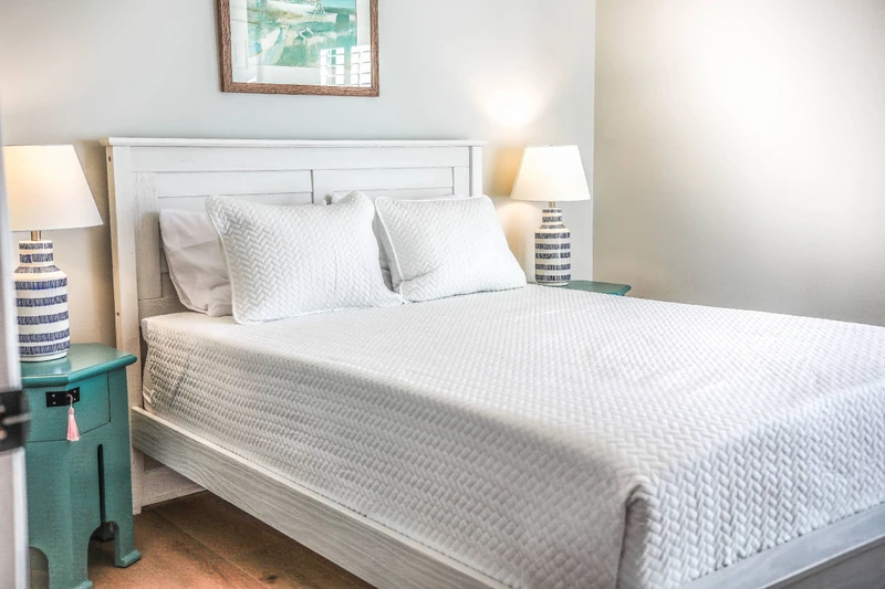 This guest bedroom features a queen bed, night stands with reading lamps and a ceiling fan.