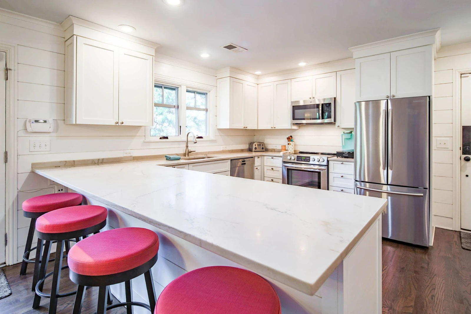 The kitchen features white cabinets, stainless steel appliances and quartz countertops.