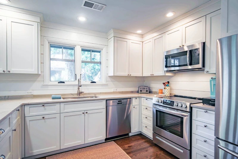 The kitchen, which is also near the front door, features white cabinetry and stainless steel appliances.