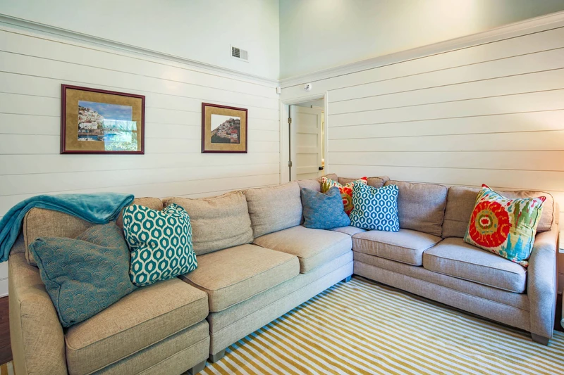 The primary suite is located off of the living room near the sectional sofa.