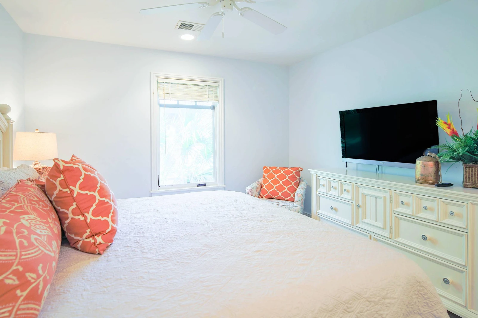 The primary suite also features a dresser, smart TV, ceiling fan and arm chair.