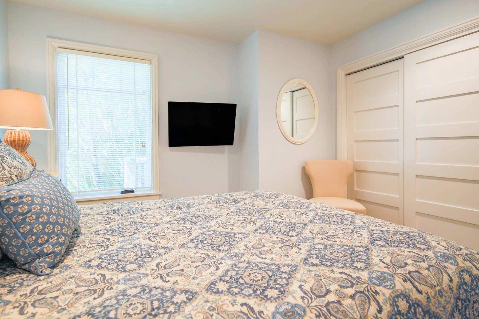 The queen bedroom also features a wall-mounted smart TV and a chair.