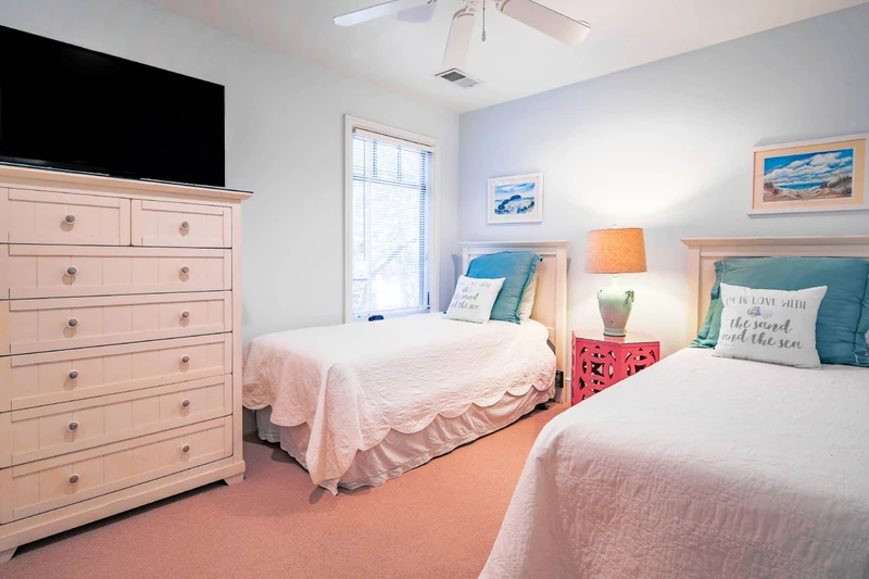 The twin bedroom also features a dresser, smart TV and ceiling fan.