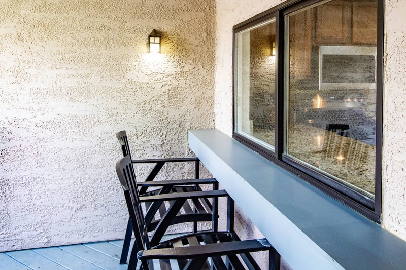There are two stools at the counter just outside the window that connects the covered balcony to the kitchen.