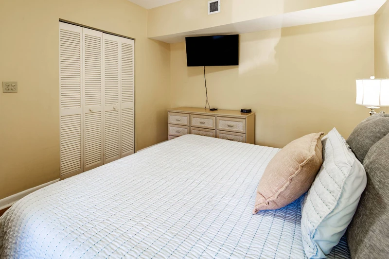The primary bedroom also features a dresser and wall-mounted smart TV.