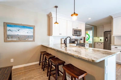 The beautiful kitchen features granite counters, white cabinets, stainless steel appliances and 4 stools.