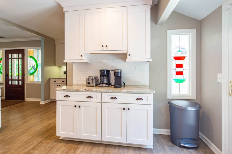 The kitchen Is located near the front door and features its own lighthouse stained glass window.