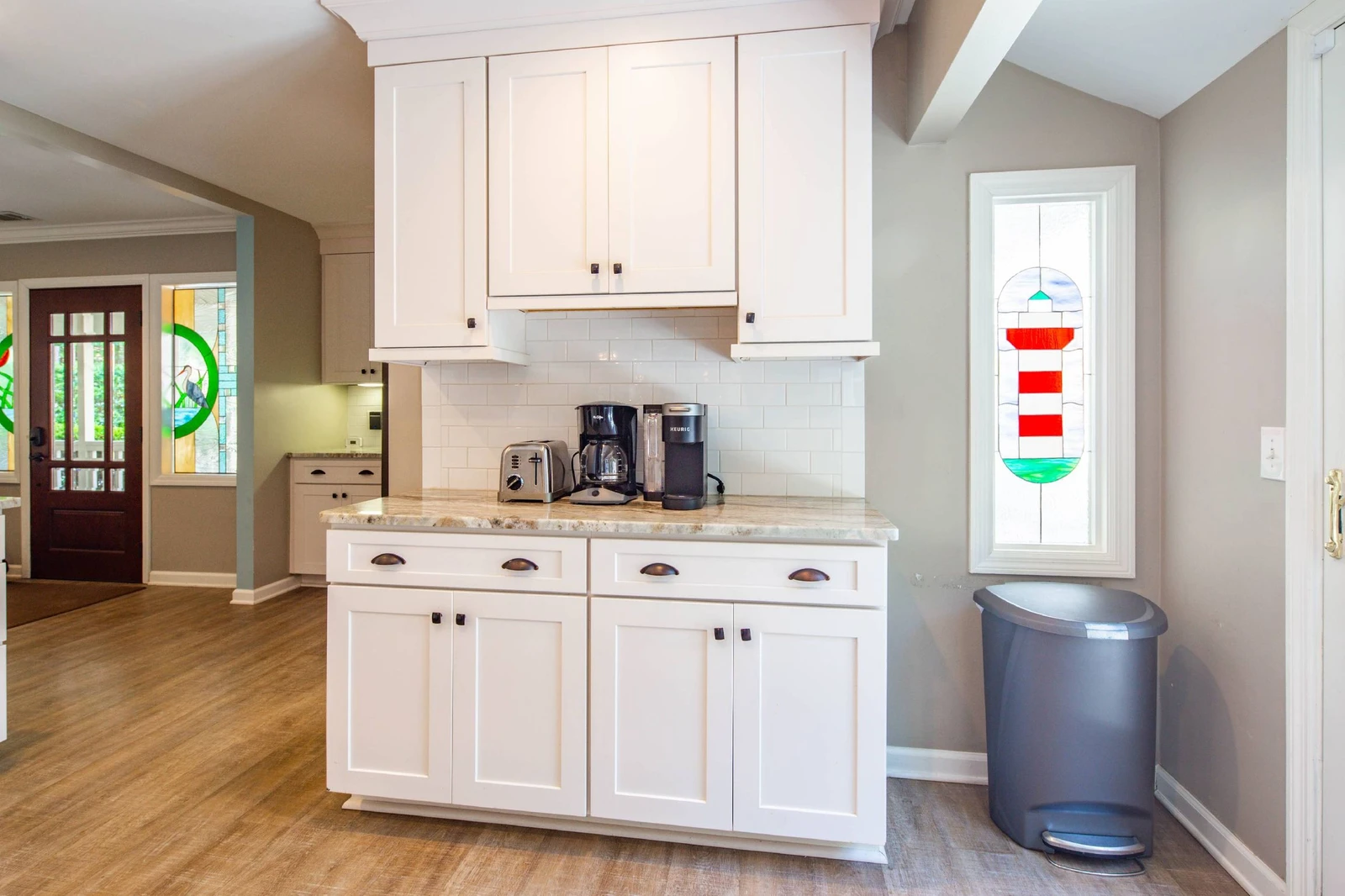 The kitchen Is located near the front door and features its own lighthouse stained glass window.