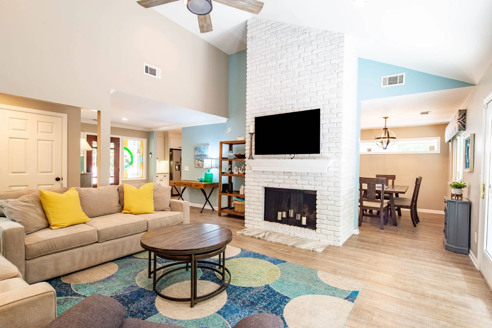 The dining area connects to the living room, with vaulted ceilings and a large screen smart TV.