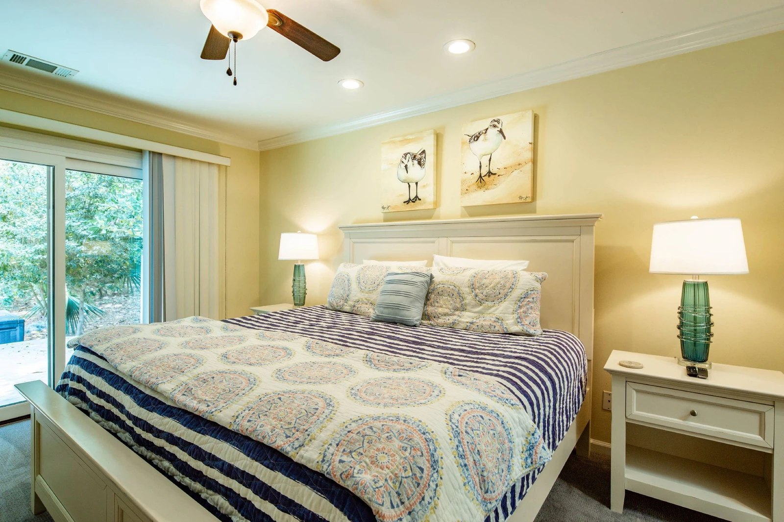 The primary suite features a king bed, night stands with reading lamps and sanderlings art work.