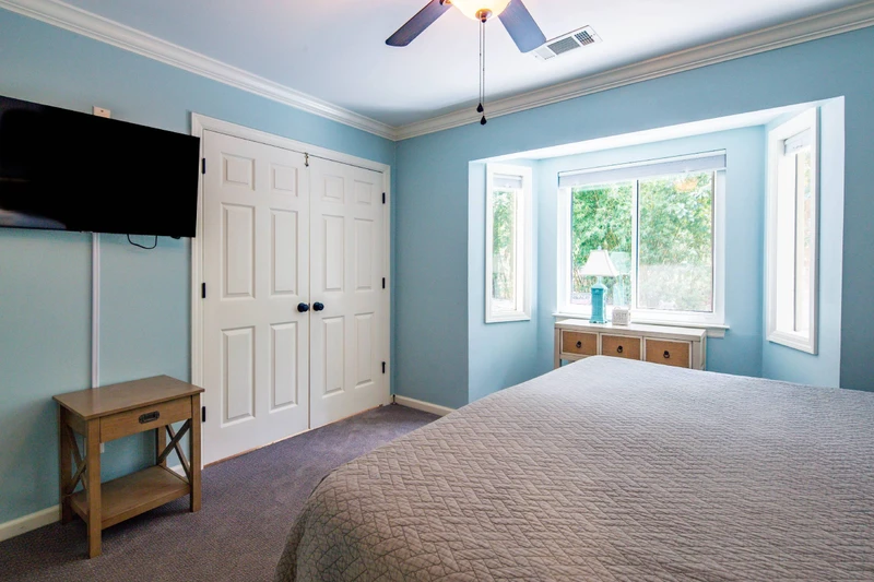 The king bedroom also features a wall-mounted smart TV, a ceiling fan and access to the living room.
