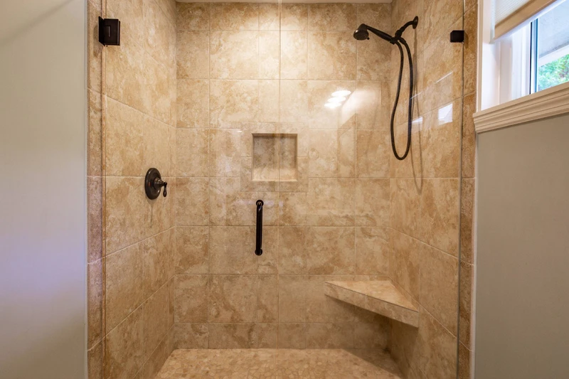 The walk-in shower has a bench and hand-held shower head.