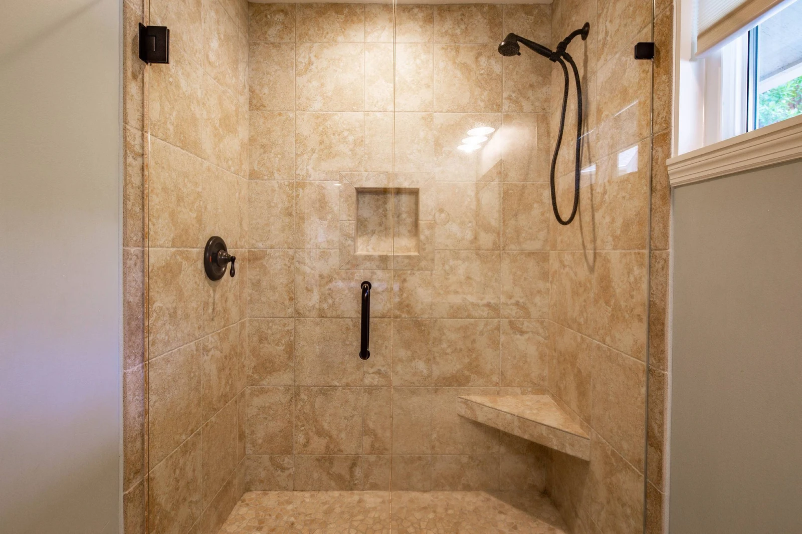The walk-in shower has a bench and hand-held shower head.