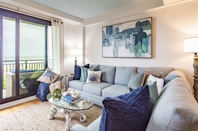 The living room features a spacious seating area, access to a balcony and ocean views.