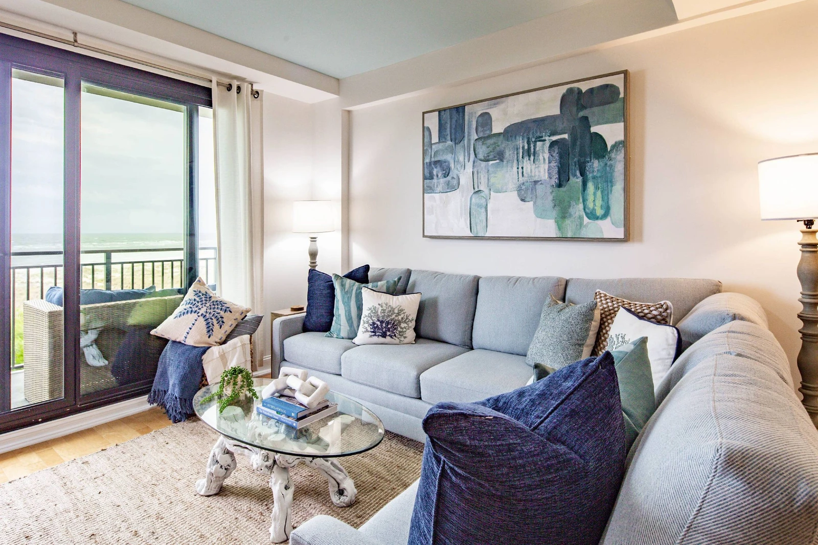 The living room features a spacious seating area, access to a balcony and ocean views.