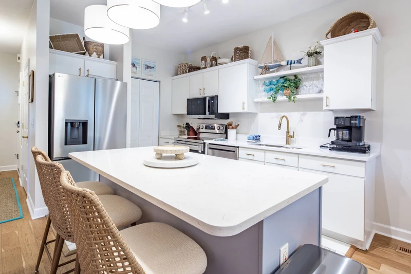 The entryway leads to the kitchecn with a central island and white cabinets.