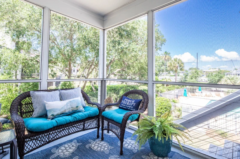 The screened porch features a comfortable seating area with views of the community pool below.