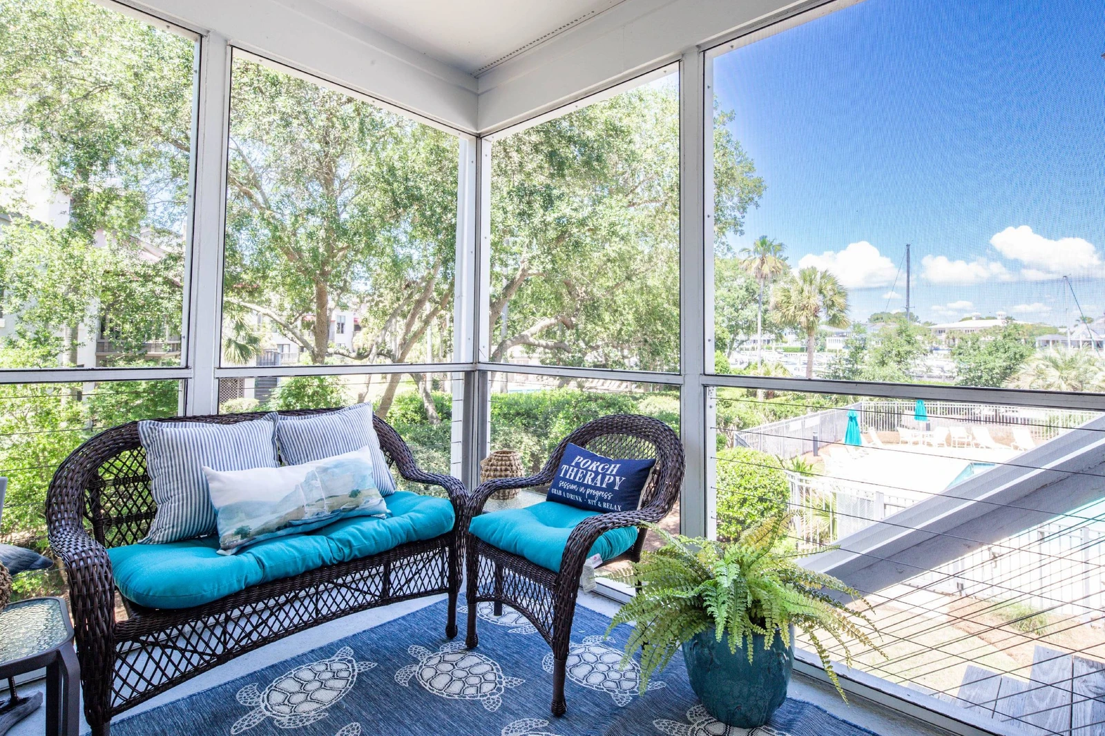 The screened porch features a comfortable seating area with views of the community pool below.