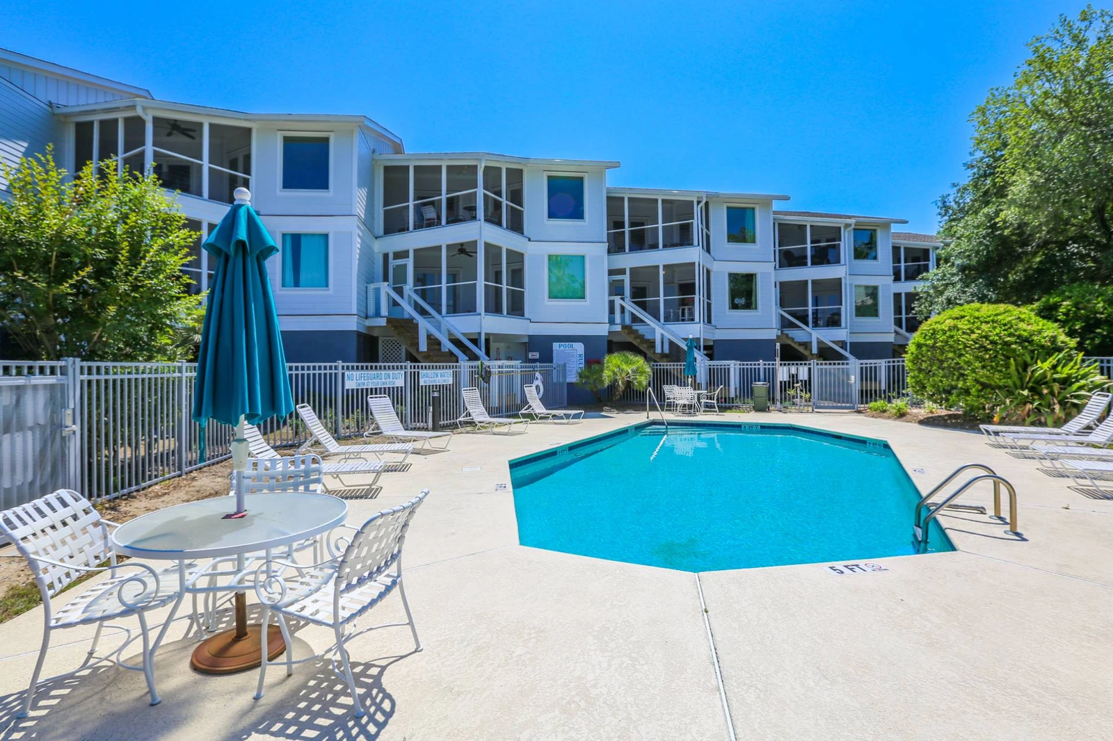 The community pool also features outdoor dining tables and chairs with umbrellas.