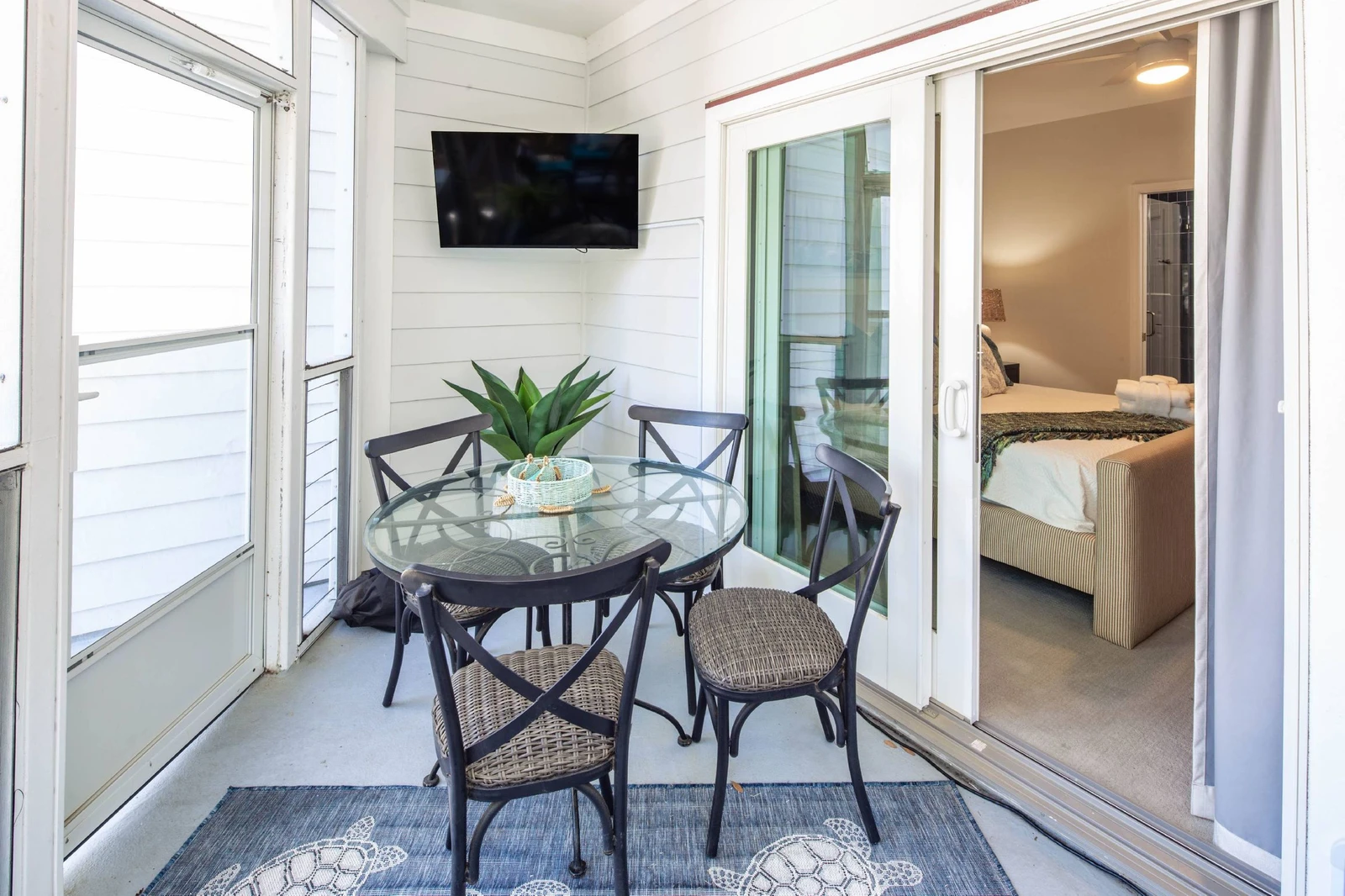 There is an outdoor dining table & chairs and a wall-mounted TV on the screened porch.