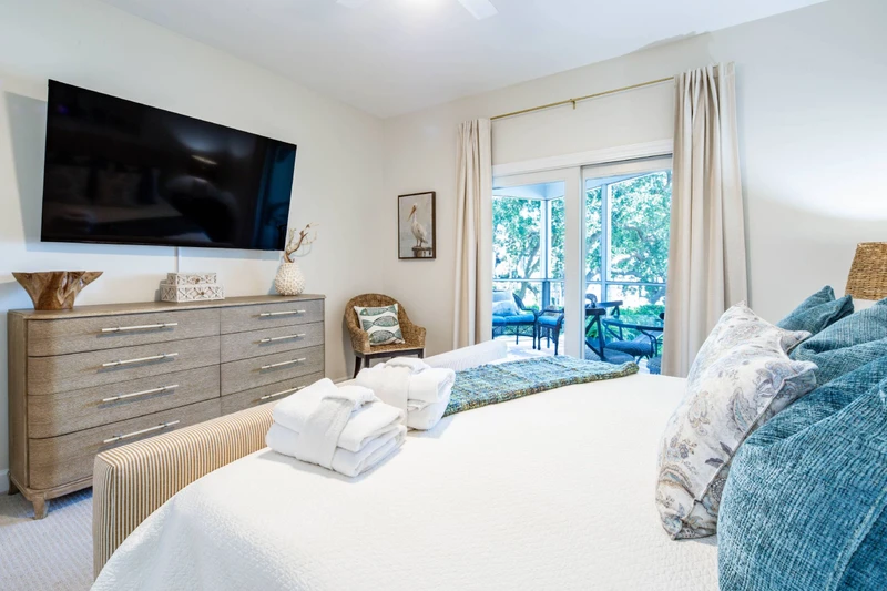 The primary suite also features a dresser, chair and wall-mounted TV.