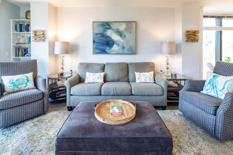 The living room has a sofa, an ottoman and multiple arm chairs & end tables.