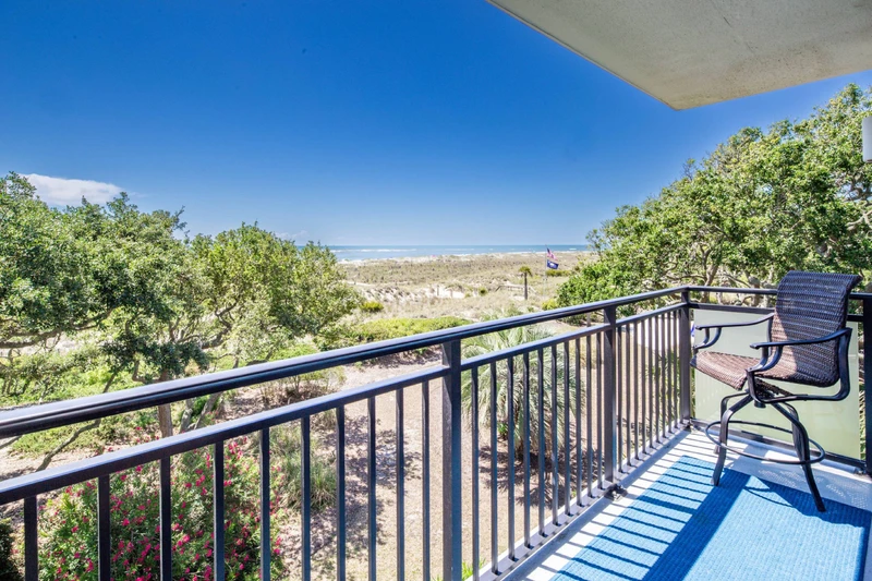The partially covered private balcony features views of the ocean, beach and sand dunes below.