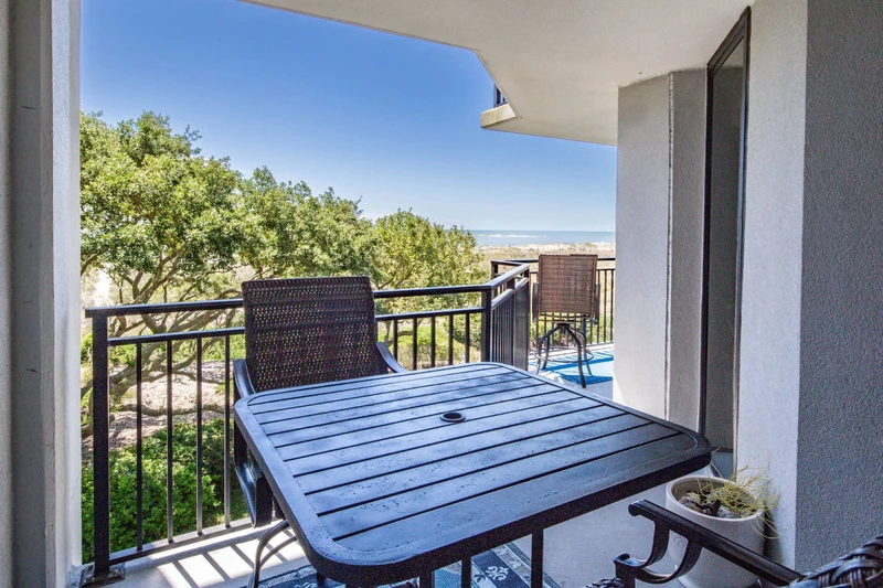 Step out onto the private balcony from the primary suite to find this high top table and chairs.