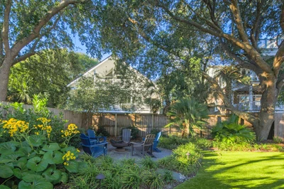 There are Adirondack chairs and a fire pit in the beautifully landscaped backyard.
