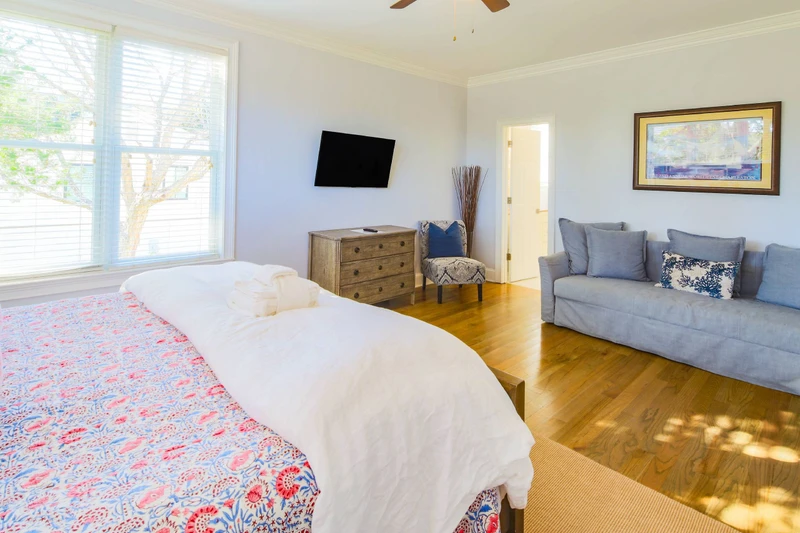 This lower level primary suite also has a mounted, streaming TV, dresser and a seating area.