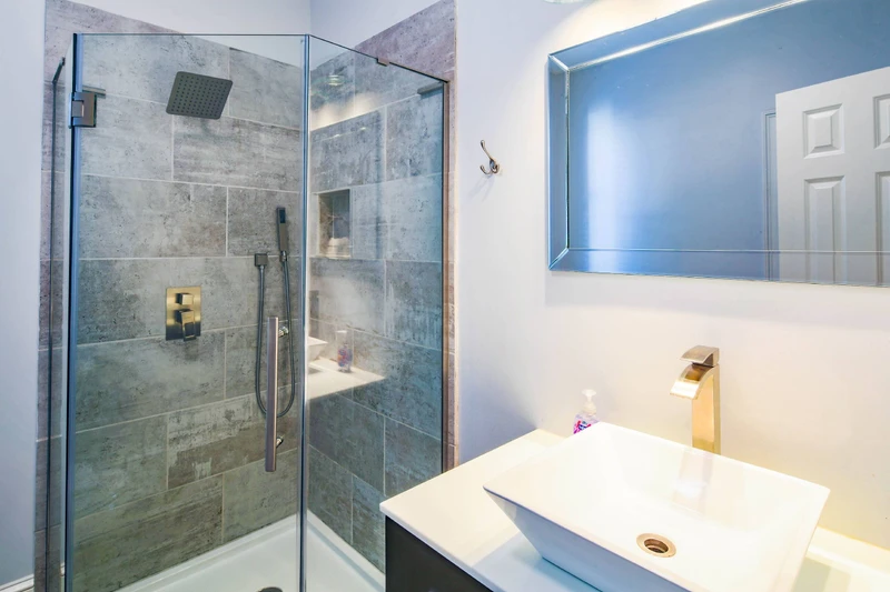This bathroom features a tiled, walk-in shower and a vanity.