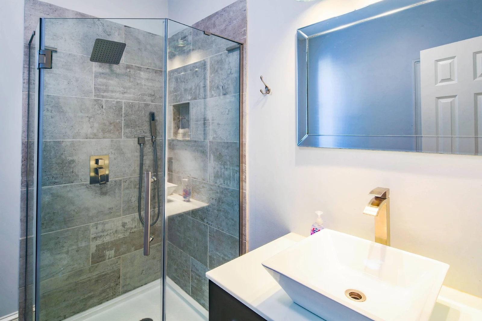 This bathroom features a tiled, walk-in shower and a vanity.