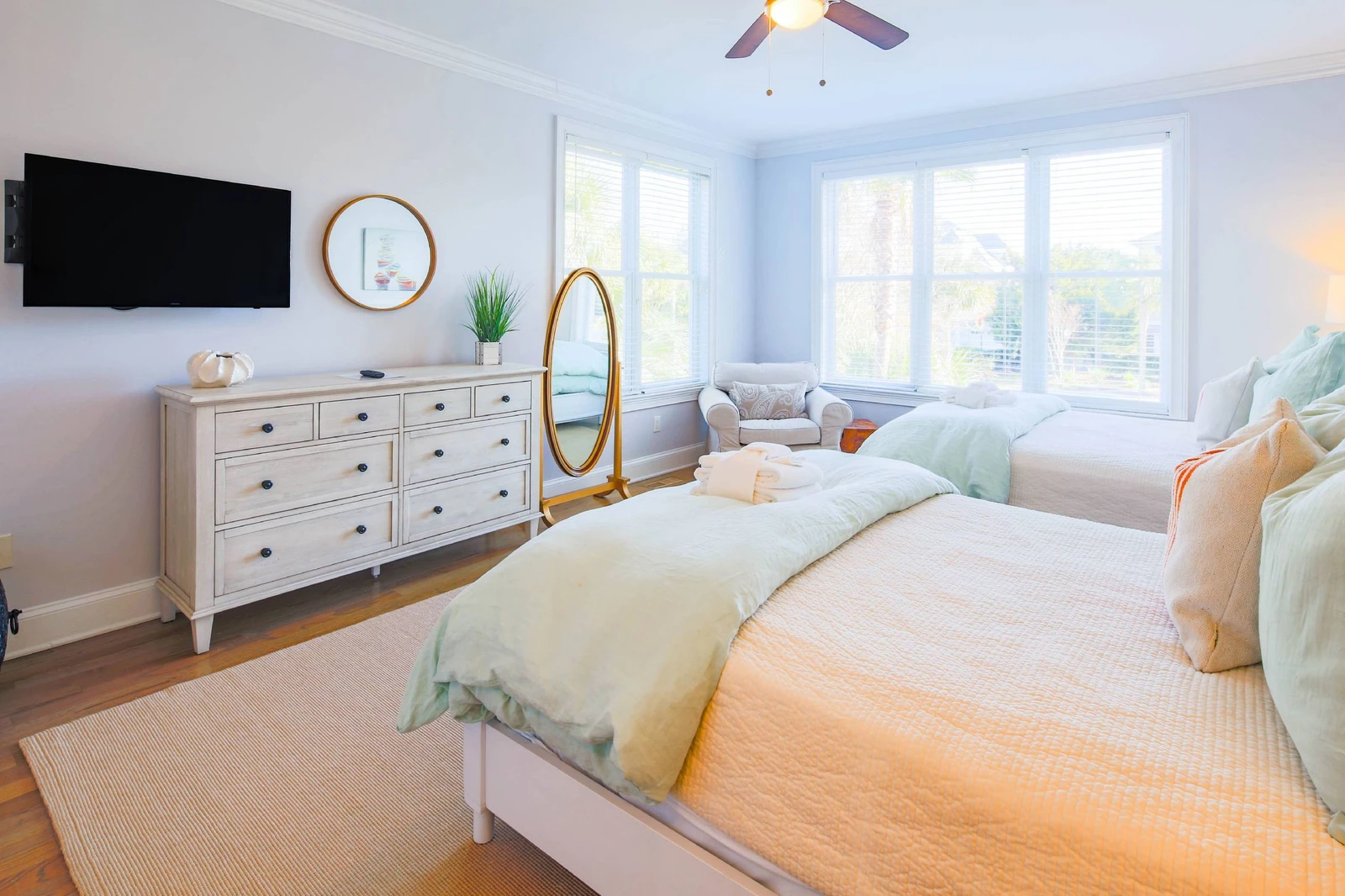 This guest bedroom has a dresser, arm chair and wall-mounted streaming TV.