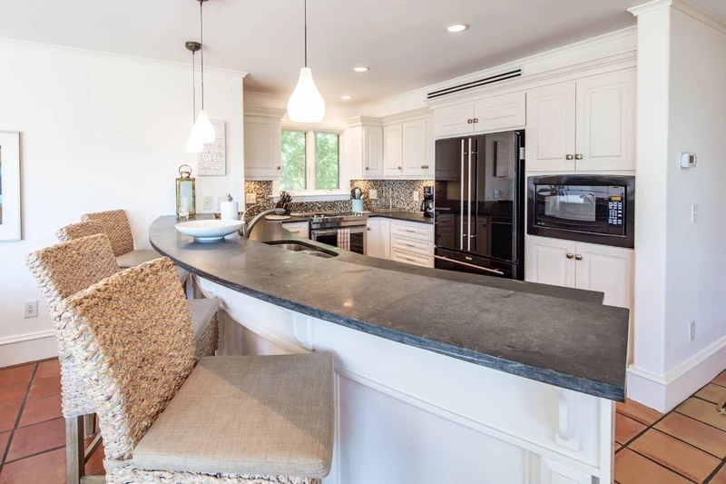 The beautiful kitchen features white cabinets, tiled backsplash and stone countertops.