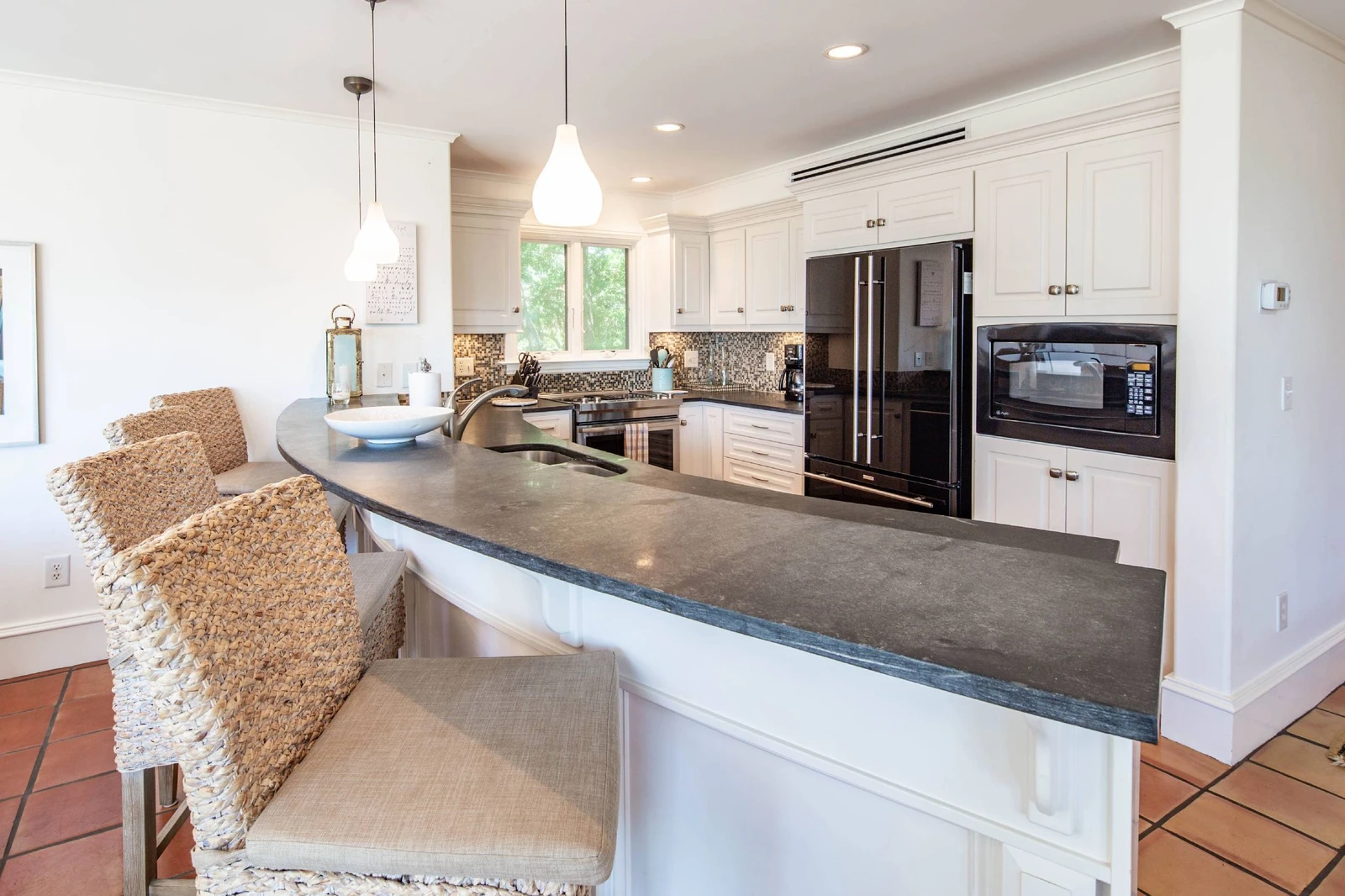 The beautiful kitchen features white cabinets, tiled backsplash and stone countertops.